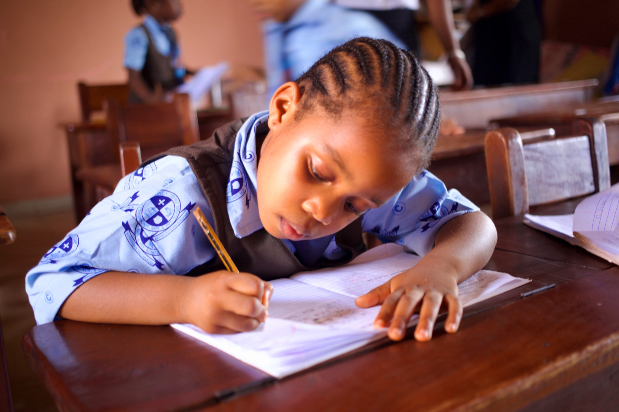 A student concentrating on writing in an exercise book.