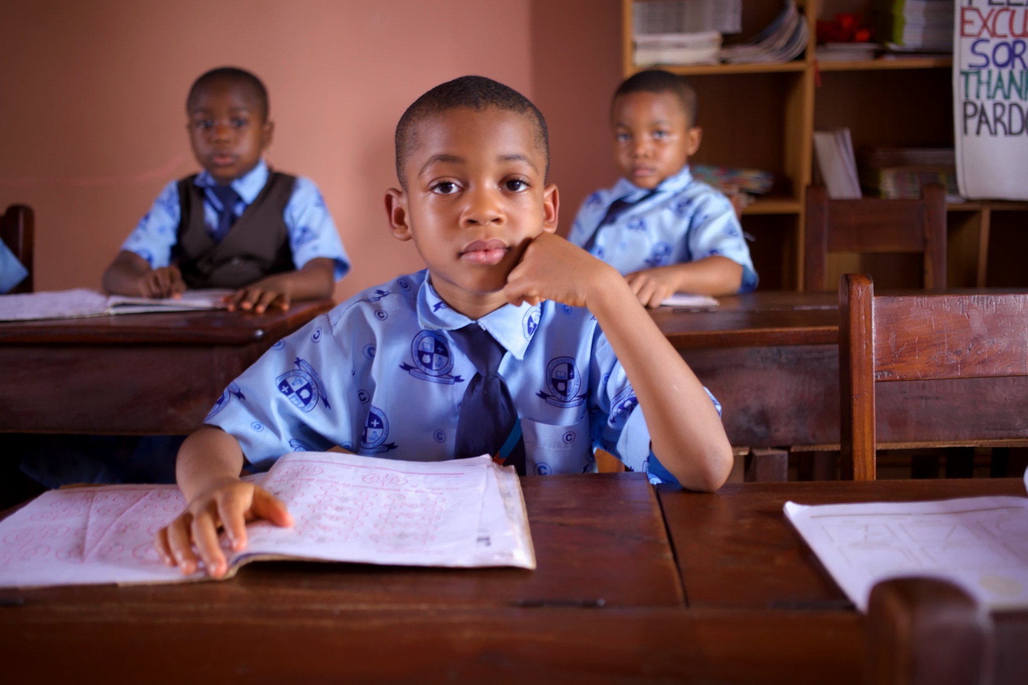 Students seated at desks with open exercise books.