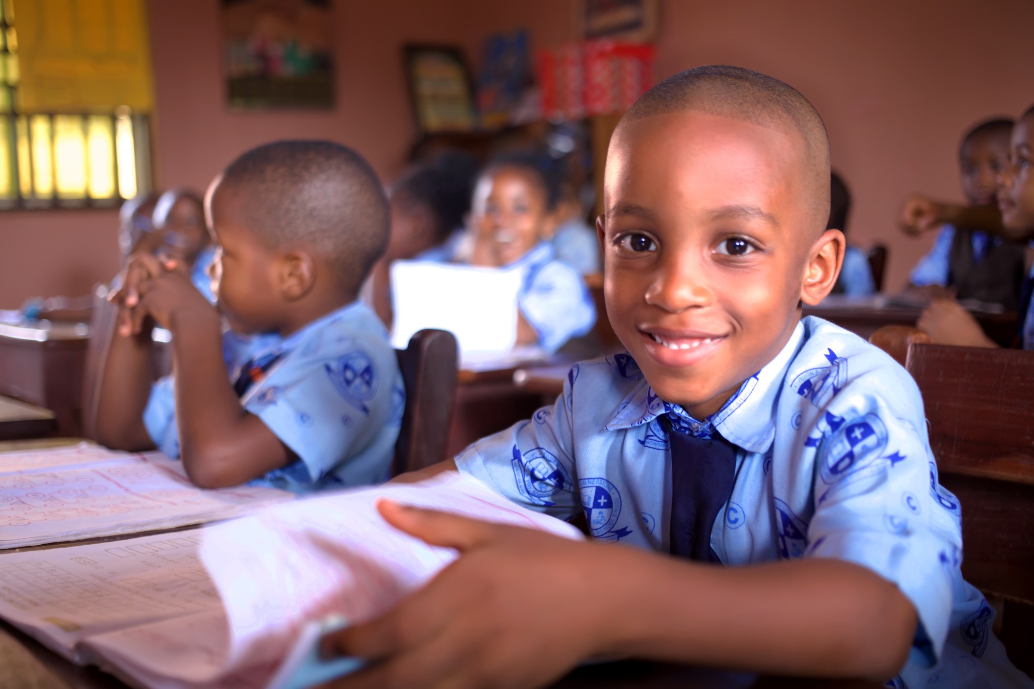 A student smiling at a classroom desk.