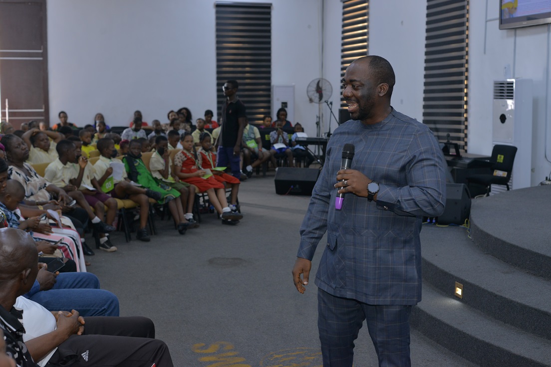 A speaker addressing participants in an event hall.